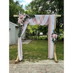 a pink and white wedding arch with flowers on the front lawn at an outdoor venue