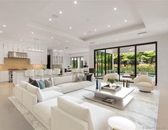 a living room filled with white furniture and lots of windows