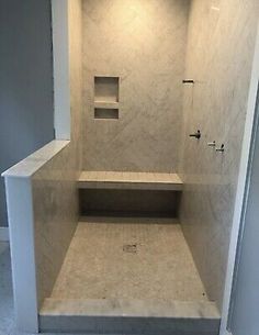 a walk in shower sitting next to a white wall and floor with no doors on it