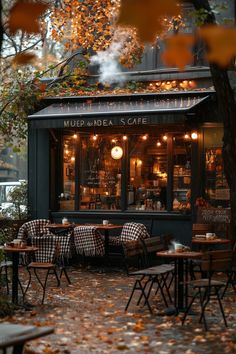 the outside of a restaurant with tables and chairs in front of it on an autumn day