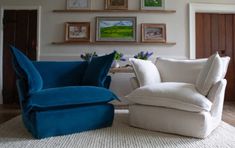 two white chairs sitting next to each other on top of a rug in front of pictures