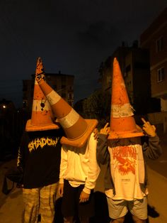 three people wearing orange and black hats with their hands in the air while standing next to each other