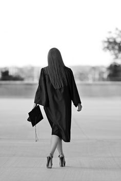 a woman in a graduation gown walking down the street with her hand on her hip