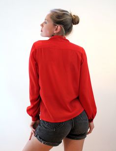 "This is a sweet 80s vintage blouse in silky tomato red polyester chiffon, with nice details that make it special. The front has extensive pintucked pleats, and a scalloped edge placket and peter pan collar with eyelet lace cut-outs and red-on-red embroidered roses. The long sleeves have single button cuffs and the blouse closes with six hidden red pearly buttons. This blouse is in very good clean vintage condition, no flaws noted. The label says \"Susan Hutton, 100% Polyester, Made in Taiwan RO Long Sleeve Tops For Vintage Fashion, Vintage Red Collared Blouse, Red Collared Vintage Blouse, Vintage Red Long Sleeve Blouse, Vintage Solid Blouse For Fall, Vintage Blouse For Fall, Vintage Red Blouse For Fall, Vintage Red Blouse For Daywear, Vintage Solid Color Blouse For Daywear