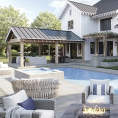 an outdoor patio with fire pit and seating area next to a swimming pool in front of a large white house