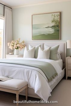 a white bed sitting next to a window in a bedroom with a painting on the wall