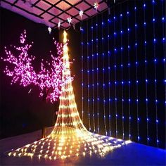 a lighted christmas tree in the middle of a room with blue and purple lights on it