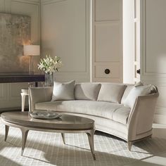 a living room filled with furniture and a large white flower vase on top of a coffee table