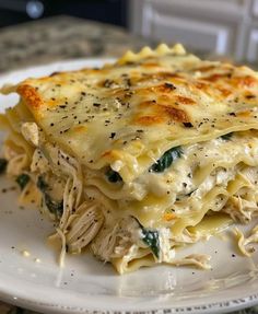 a white plate topped with lasagna covered in cheese and spinach toppings