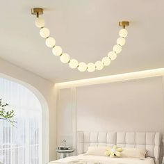 a white bed sitting in a bedroom next to a window with lots of lights on it