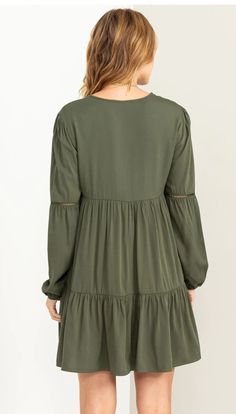 This dress features a V-neck, long sleeves with cinched cuffs, partial button detail at the bodice, and a tiered silhouette that enhances movement. Pair with western boots for a complete look. The model is 5'9" Tall, 34C Chest, 24" Waist, and 34: hips, and Wearing a size small. Green Bishop Sleeve Dresses For Fall, Green Bishop Sleeve Dress For Fall, Green V-neck Long Sleeve Dress For Fall, Fall Dresses With Ruffle Hem And Bishop Sleeves, Milly Dress, Tiered Mini Dress, Perfect Wardrobe, Green Button, Fall Looks