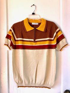 Brand new!! Never tried on!! Ordered wrong size by mistake. This is a wonderful sweater top for your vintage man!! Retro ribbed polo top in beige, brown, gold, and maroon. Vintage 70s style stripe panel detailing. Zip neck. Fabric: Cotton, Lycra, Polyester. Care: Machine wash, dry flat. Men's Size Small. Retro Collared Polo Sweater For Fall, Brown Short Sleeve Polo Shirt For Fall, Retro Collared Sweater For Fall, Brown Short Sleeve Tops With Ribbed Collar, Fitted Brown Polo Top, Brown Short Sleeve Sweater For Fall, Retro Brown Top For Winter, Retro Brown Winter Top, Retro Polo Collar Tops For Fall