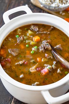 a white bowl filled with soup next to a wooden spoon on top of a table