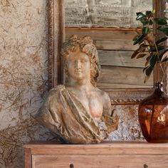 a busturine sitting on top of a dresser next to a vase and mirror