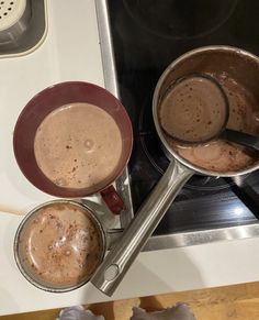 two pans filled with hot chocolate sitting on top of a stove