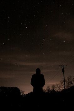 a person standing in the dark looking up at the stars