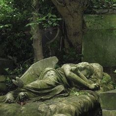 a statue is laying on the ground in front of some trees and bushes, with its head resting on it's back