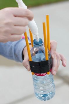 a person holding a water bottle with several yellow and blue straws sticking out of it