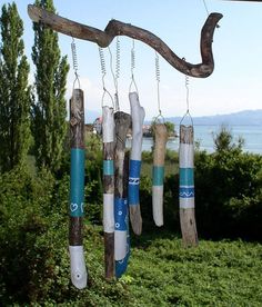 a wind chime hanging from a tree branch in front of some water and trees