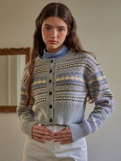 a woman standing in front of a mirror wearing a sweater and skirt with buttons on it