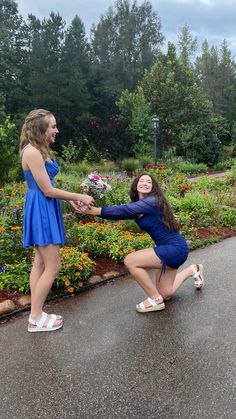 two girls in blue dresses are holding hands and smiling as they stand on the road