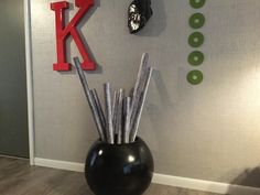 a black vase filled with umbrellas sitting on top of a wooden floor next to a wall