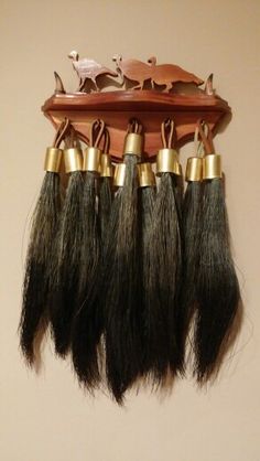 several pieces of hair hanging from a wooden rack with gold trimmings on it