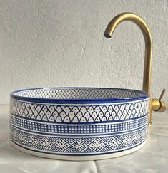 a blue and white bowl with a gold faucet on the top is shown