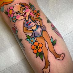 a woman's leg with tattoos on it and flowers around her legs, including an orange sun