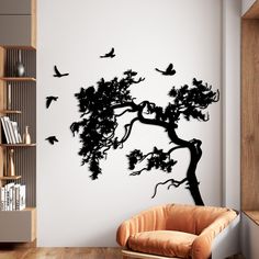 a tree with birds flying around it on the wall in a living room, next to a brown chair