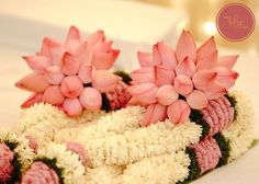 pink and white flowers are placed in the shape of a flower arrangement on a table