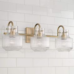 three light bathroom fixture with clear glass shades on the bottom and brass fixtures above it