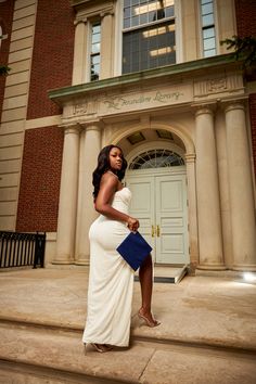 a woman in a white dress is standing on the steps with a blue clutch bag