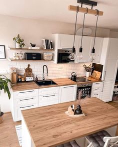 a kitchen with white cabinets and wooden counter tops, an island in front of the sink