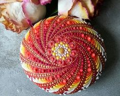 some flowers are sitting on the ground next to a round object that is decorated with beads