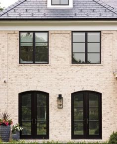 a white brick house with black doors and windows