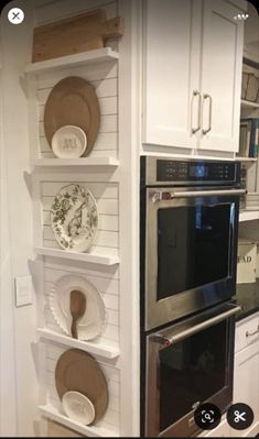 a kitchen with white cabinets and black stove top oven in the center, plates on shelves above it