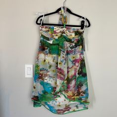 a multicolored dress hanging on a hanger next to a light switch box