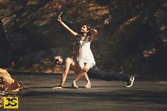 a man and woman are dancing on the street with their arms up in the air