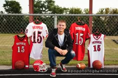 a young man sitting in front of sports jerseys and basketballs on the sidelines