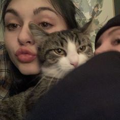 a woman holding a cat in her arms and sticking its tongue out to the camera