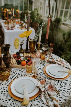 the table is set with plates, candles and other items for an elegant dinner party