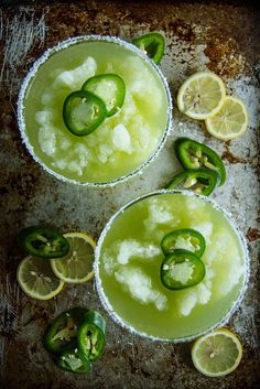 two margaritas with jalapenos and lime slices on a baking sheet, ready to be served