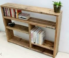 a wooden shelf with books and a potted plant sitting on it's side