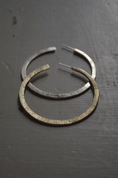 Made in brass fused with silver, with textures made by hand to give them an aged look. One of its faces is made of brass and the other of molten silver, which allows variations depending on the views or the way of using them. Reversible. The posts are silver. Approximate diameter: 6 cm Made to order Hammered Gold Mixed Metal Jewelry, Hammered Mixed Metal Gold Jewelry, Hammered Silver Brass Earrings, Silver Hammered Brass Earrings, Hammered Bronze Metal Hoop Earrings, Brass Hoop Earrings With Oxidized Finish, Bronze Hammered Metal Hoop Earrings, Small Hoop Hammered Brass Jewelry, Handmade Silver Brass Hoop Earrings