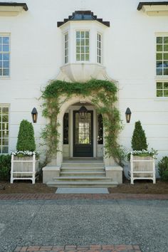 a white house with two benches in front of it and ivy growing on the wall