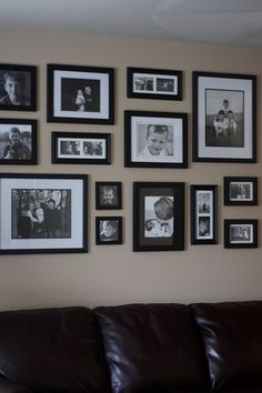 a brown leather couch sitting in front of a wall covered with black and white pictures