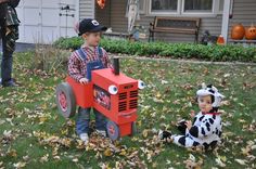 two children dressed up in costumes playing with a toy tractor