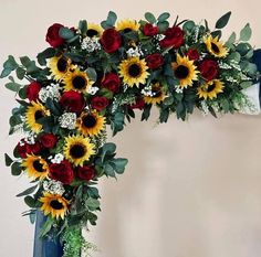 a bouquet of sunflowers and roses arranged on a blue vase with greenery