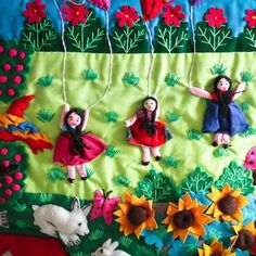 several dolls hanging from strings in front of flowers and animals on a green cloth background